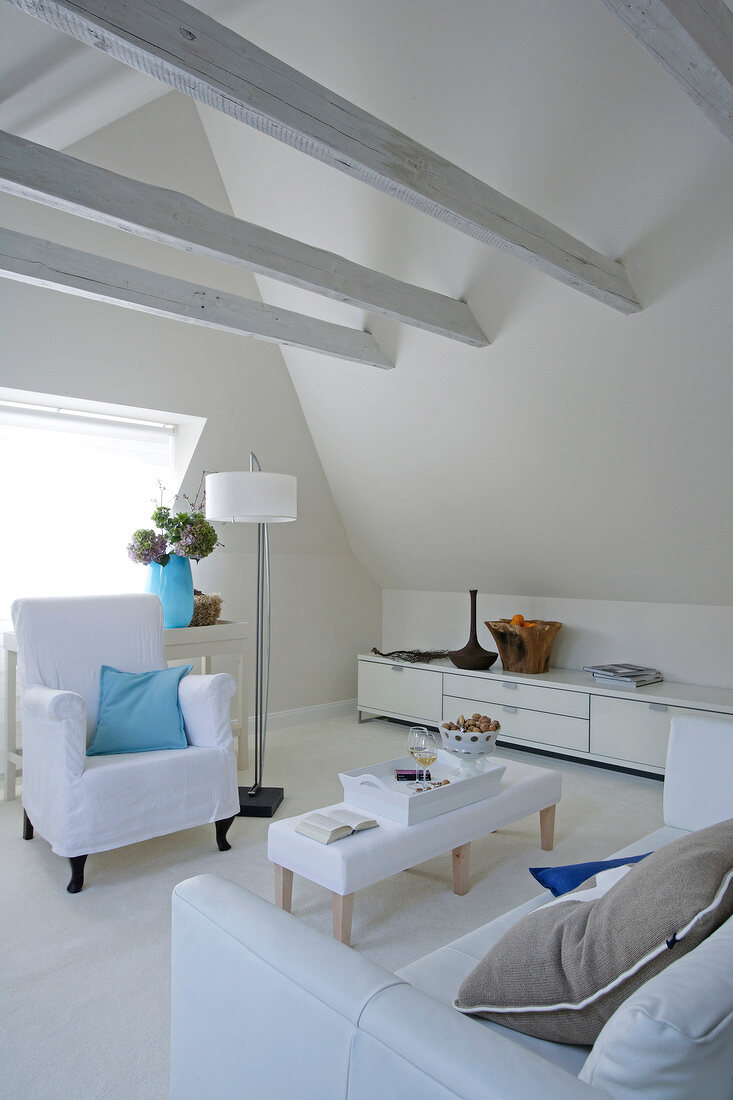 Living room with armchairs, sofa, sideboard, floor lamps and table in attic