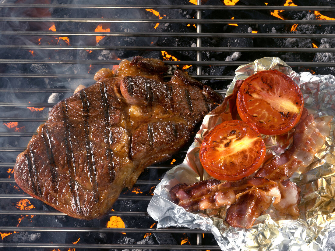 Grilled rib with tomato and bacon being grilled on barbecue