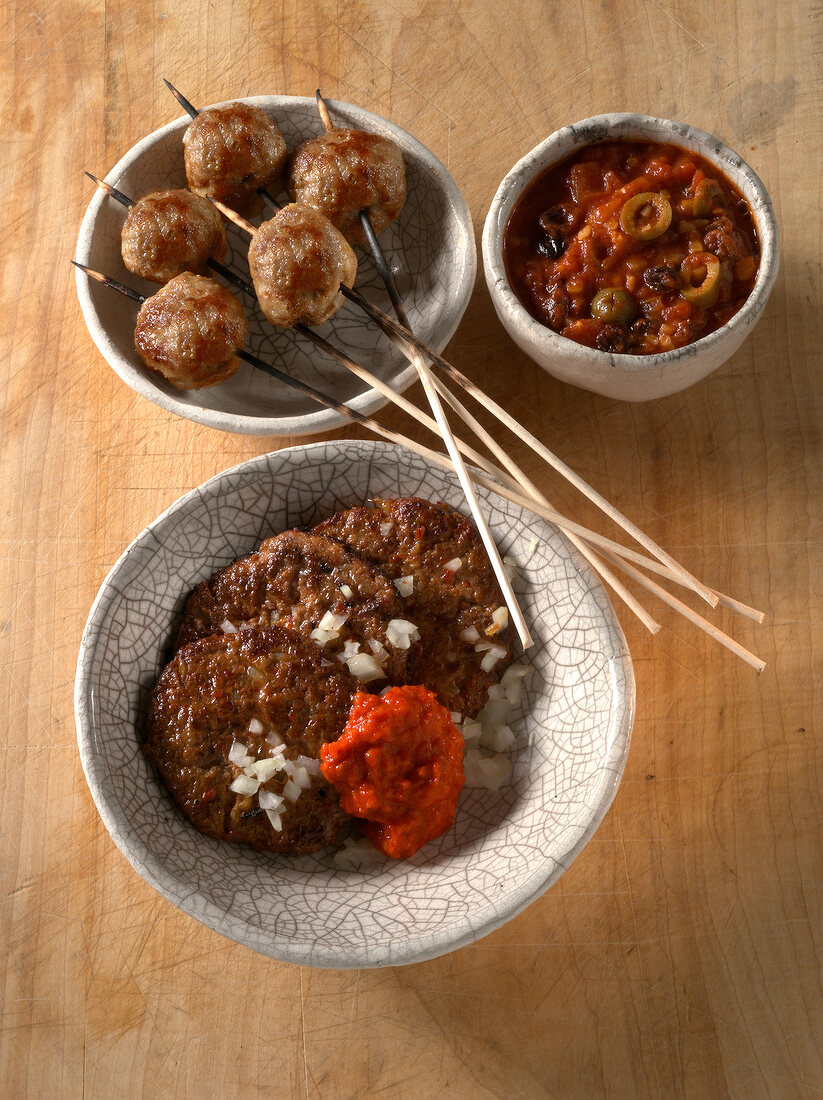 Bowls of meatballs on skewers and meatballs with chilli paste