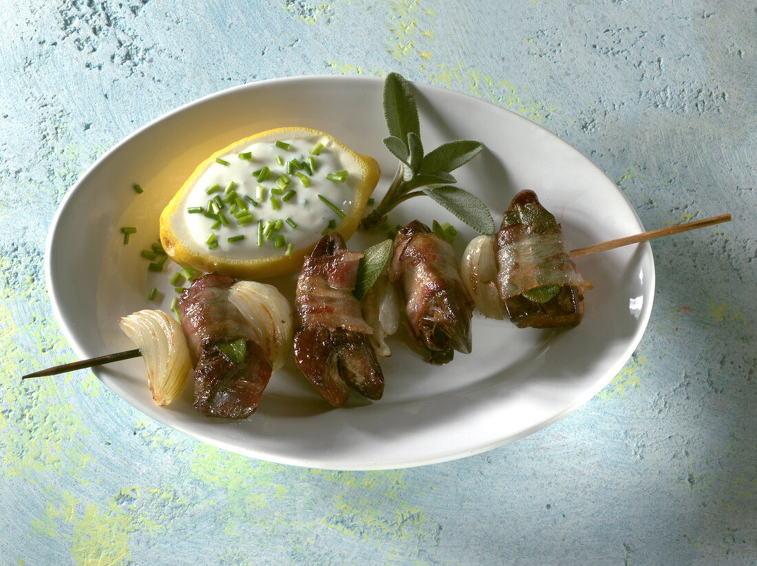 Chicken liver skewers with chive yogurt in hollowed lemon in serving dish