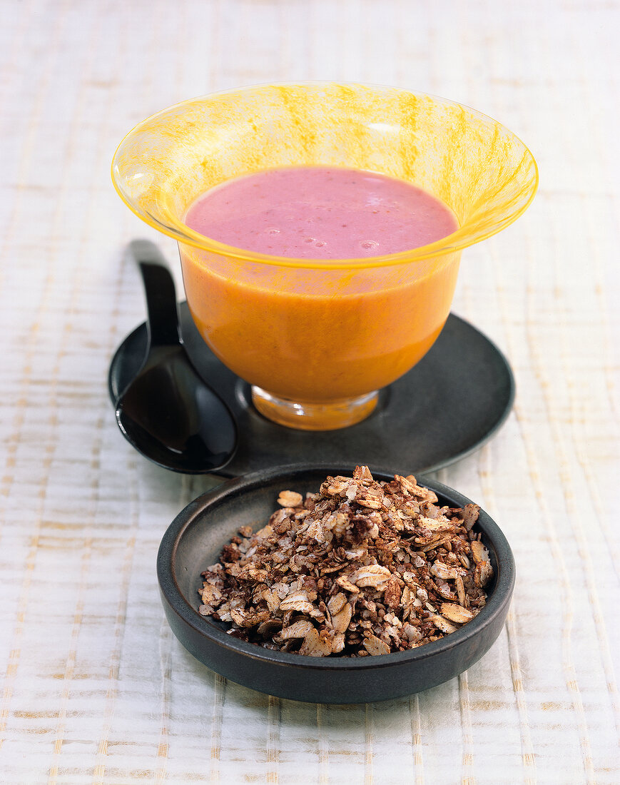 Strawberry milk in bowl with chocolate muesli in saucer