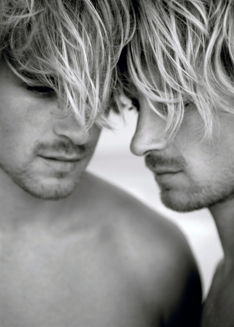 Close-up of handsome man standing and touching forehead, black and white