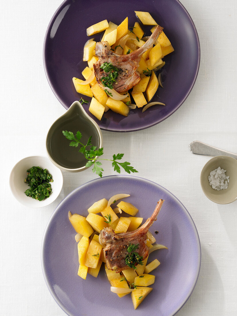 Lamb chops with swedes on purple plates, overhead view