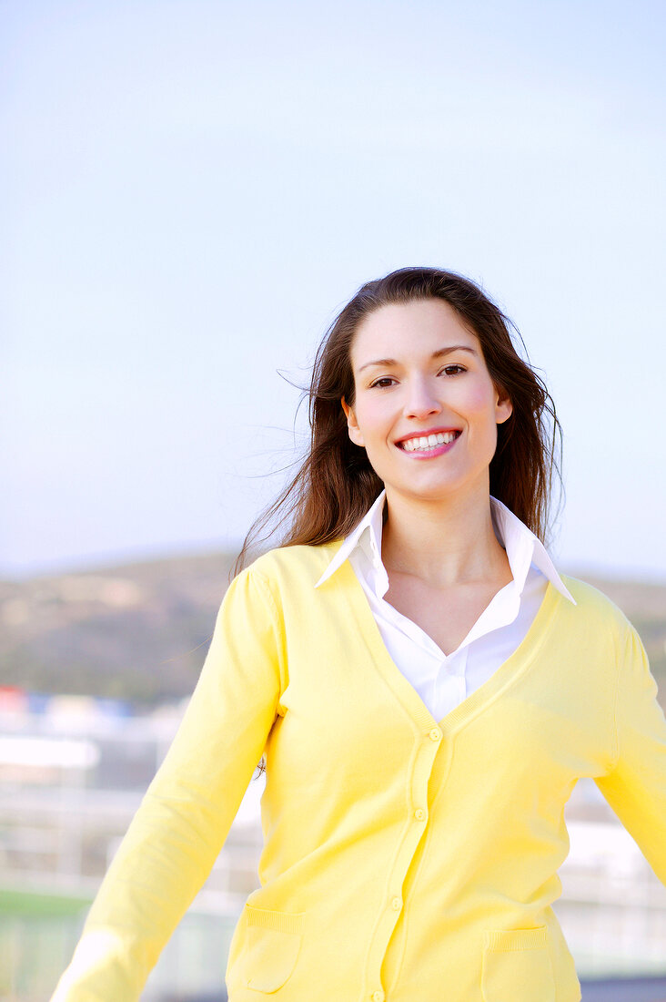 Cheerful brunette woman with long hair wearing yellow sweater, smiling