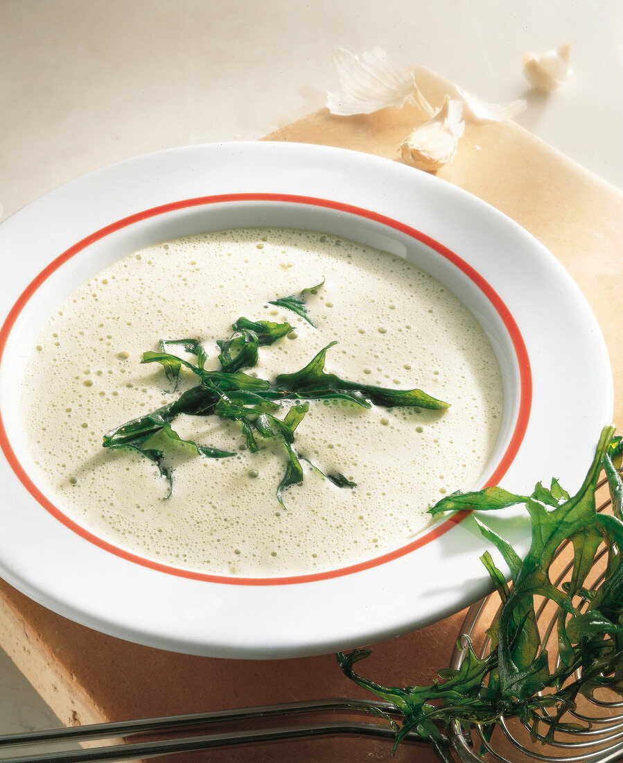 Creamy arugula soup with garlic on plate