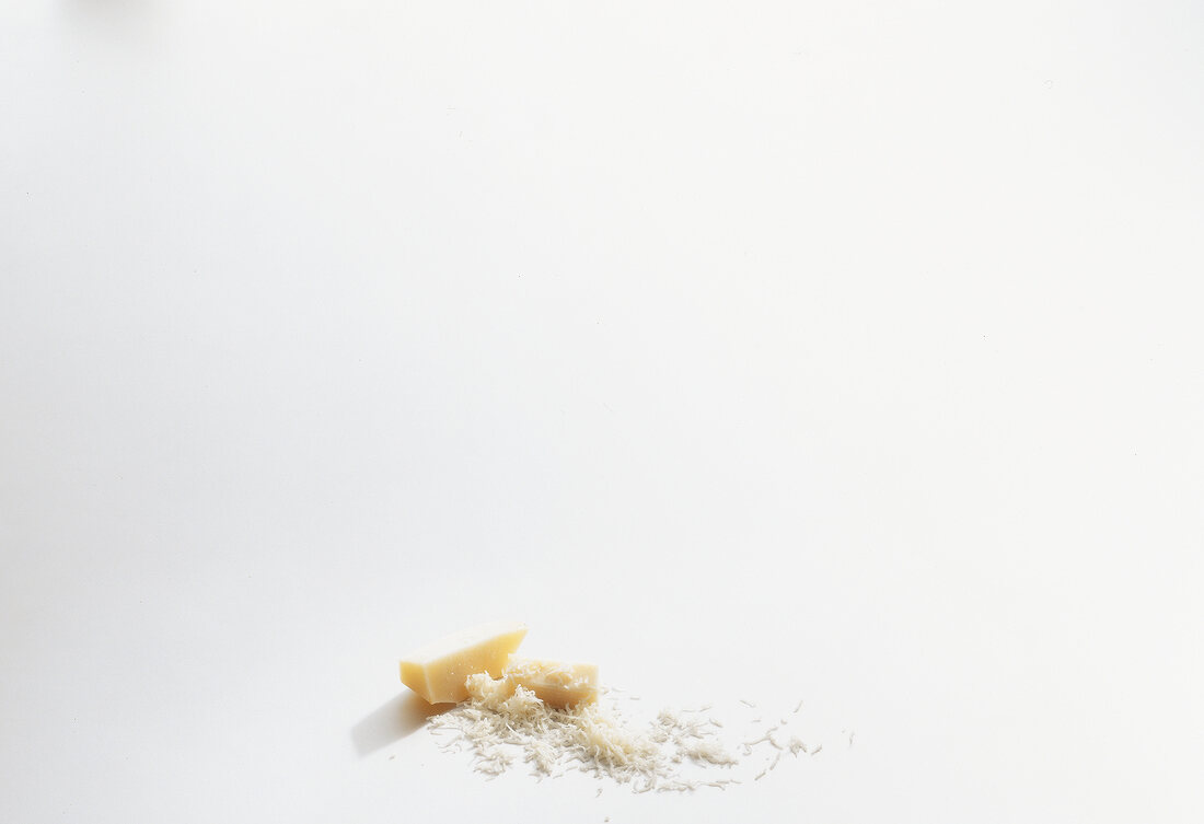 Piece of pecorino cheese and grated cheese on white background