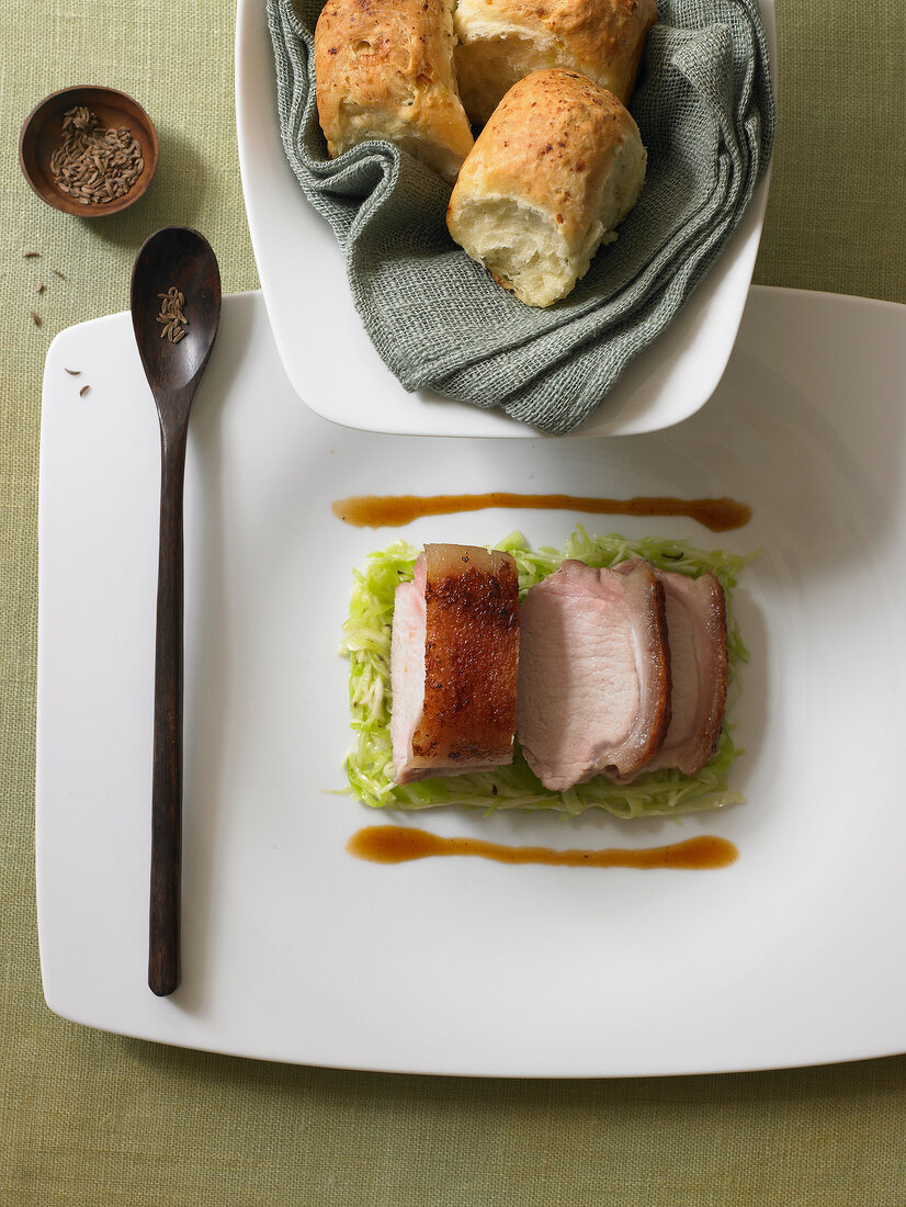 Fillet of pig on plate with savoury spiced mini buns in bowl