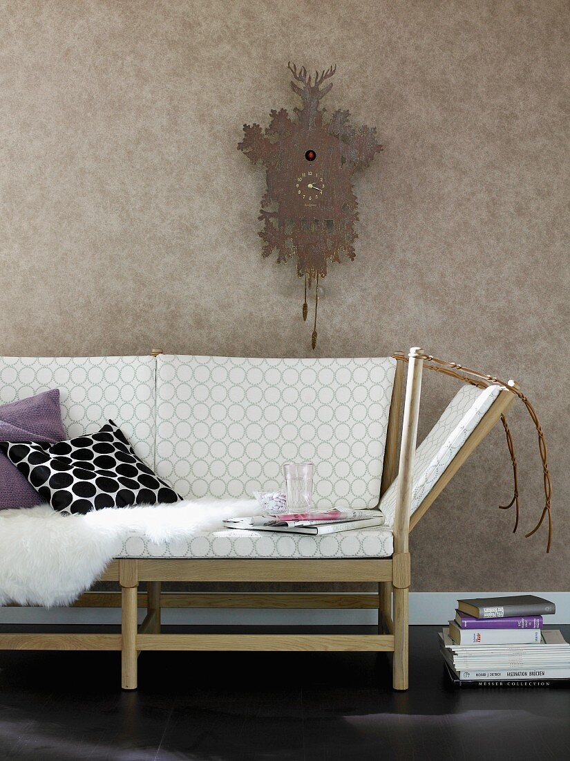Retro-look sofa with wooden frame below cuckoo clock on wall