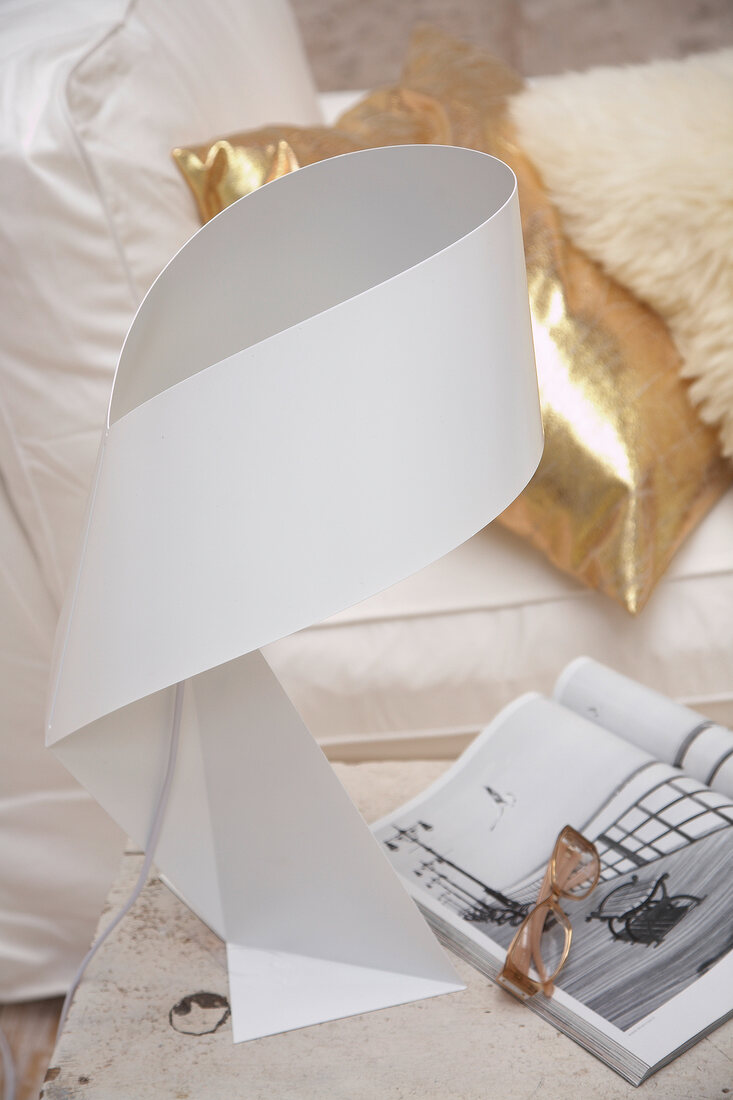 Curved table lamp with magazine and glasses on side