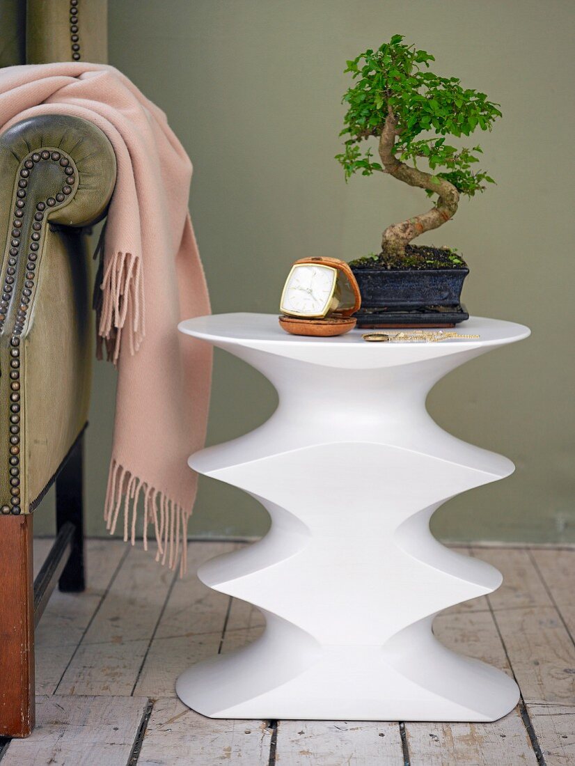 Bonsai tree on contemporary white table with concave indentations