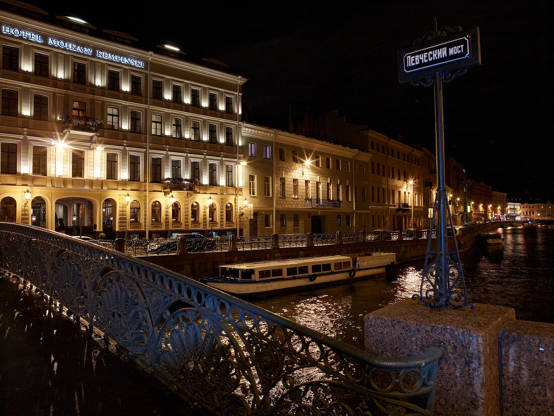 View of illuminated hotel facade at night, bridge and canal