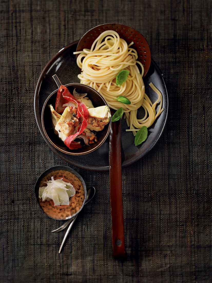 Spaghetti with artichokes and basil leaves on plate