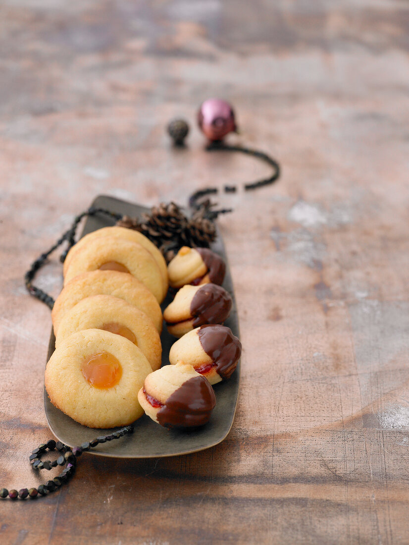 Husarenkrapfen with apricot jam and linzer cookies with chocolate icing on serving dish