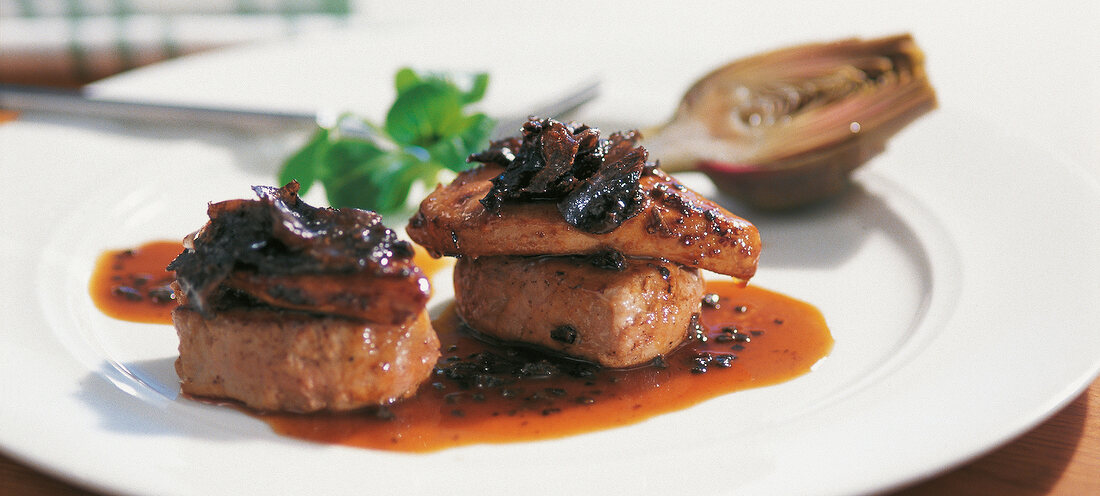 Close-up of veal fillet with truffles, foie gras and sauce on plate