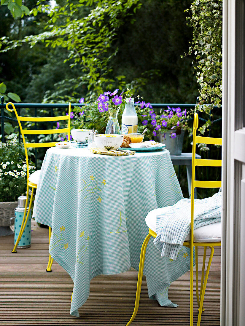 Bowls of cereal and bottle of milk laid on breakfast table for two on terrace