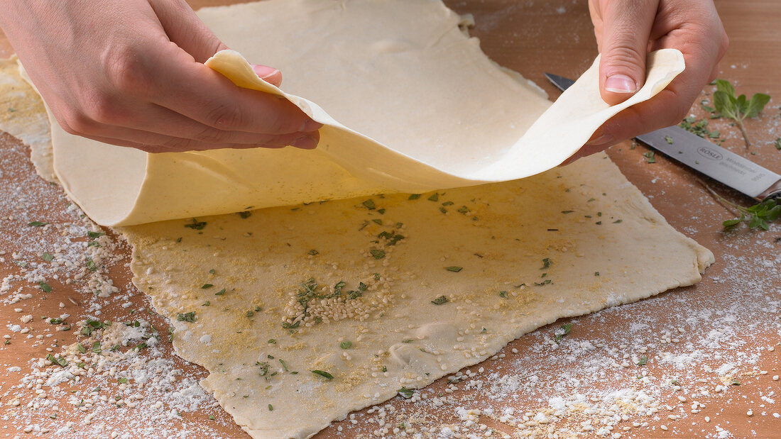 Placing one layer of dough on another layer powdered with spices