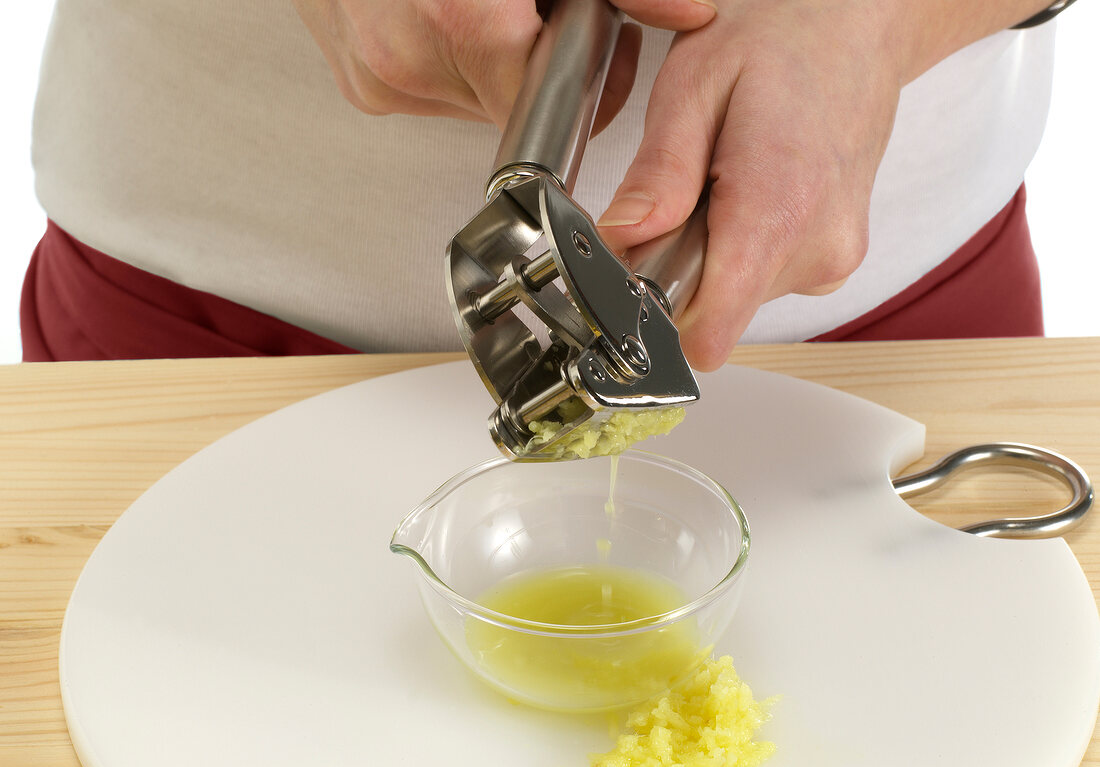 Squeezing ginger with hand juicer in glass bowl