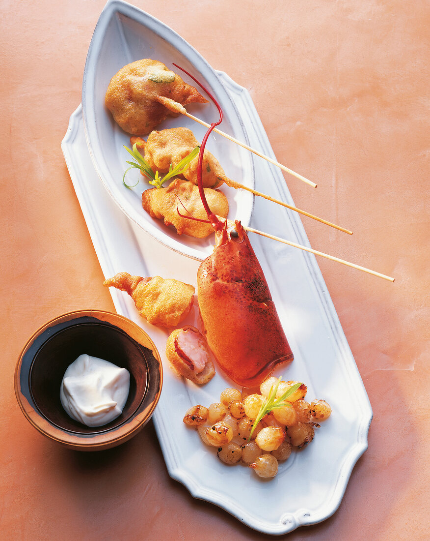 Lobster beignets in skewers with onions and sour cream on serving dish