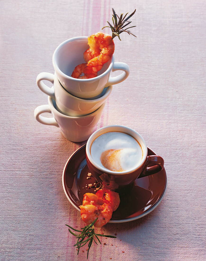 Cappuccino with shrimp skewer on stack of cups