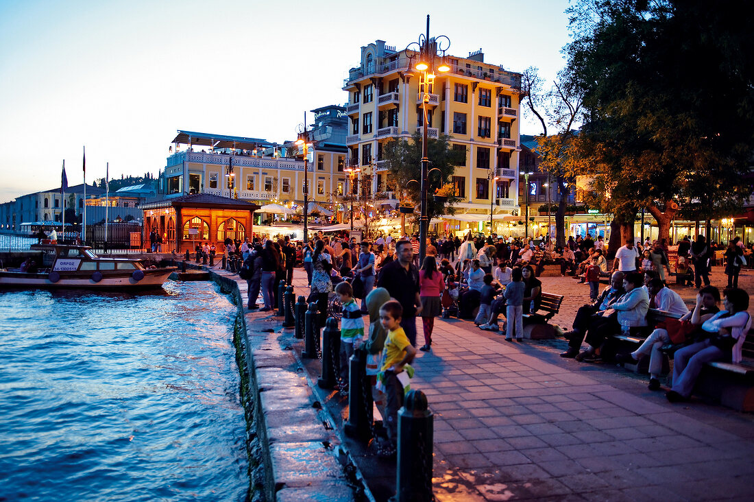 Menschen an Uferpromenade in Ortaköy abends, beleuchtet