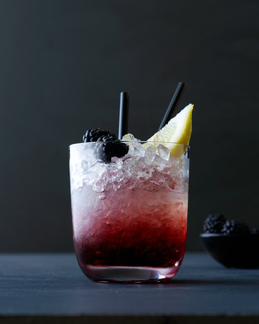 Classic bramble with lemon ice cubes and blackberries in glass