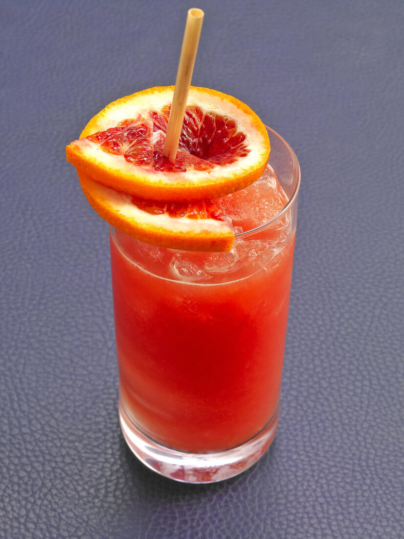 Bloody ginger cocktail with orange and ice cubes in glass
