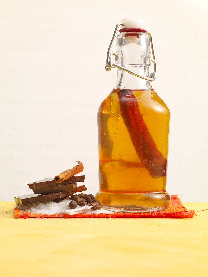 Caramel and cinnamon syrup in preserving jar with sugar, cinnamon sticks and chocolate 