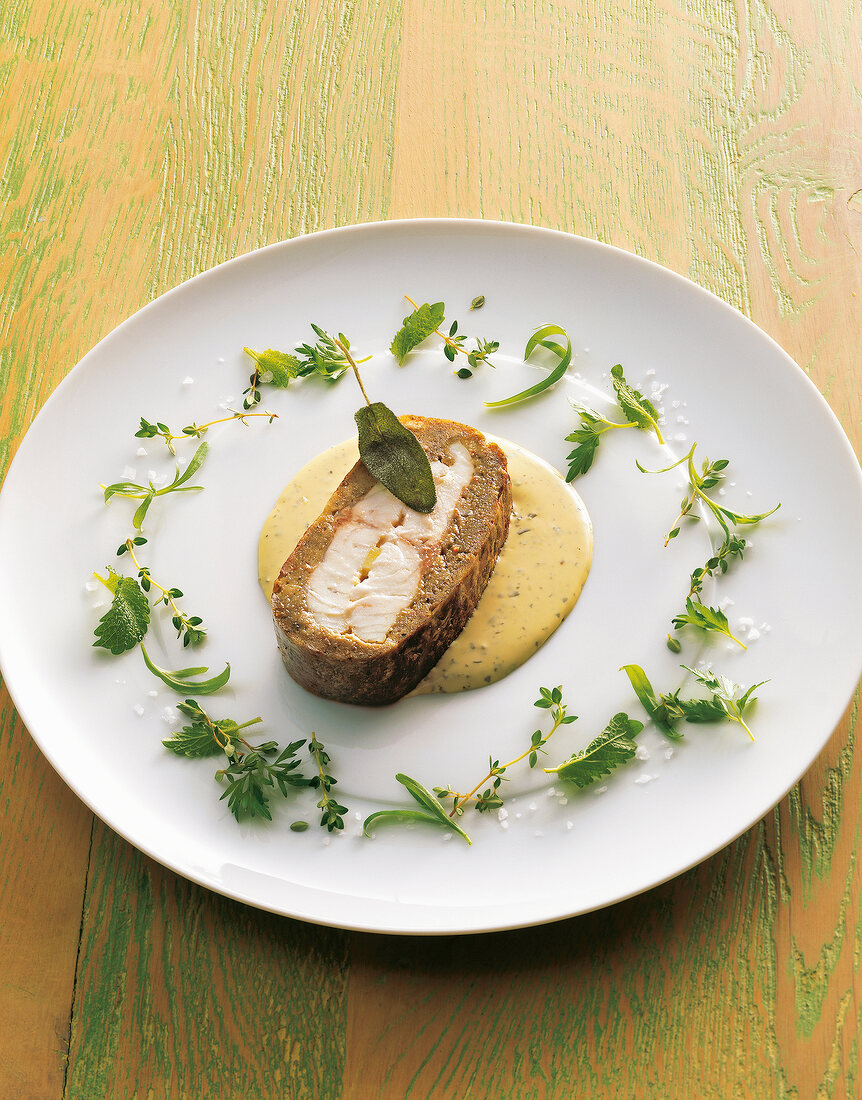 Sea bass with broth and herbs on plate