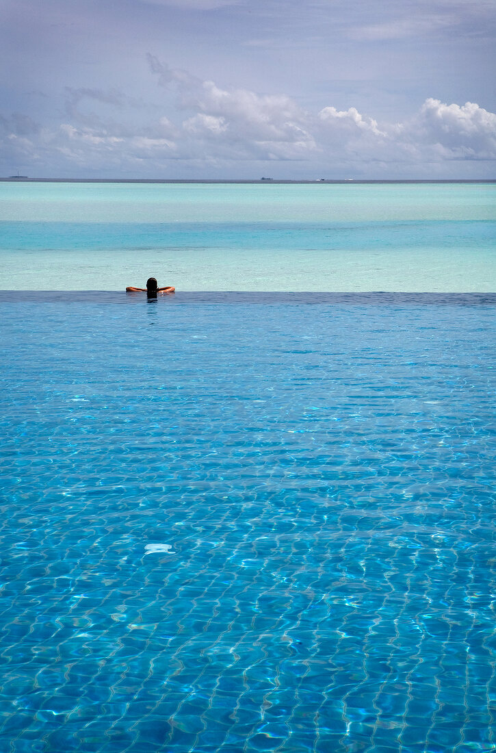 Lonely man relaxing in pool with sea in background in Dhigufinolhu Island, Maldives
