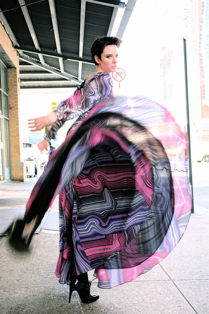 Woman swinging her dress while walking on the road, looking over shoulder