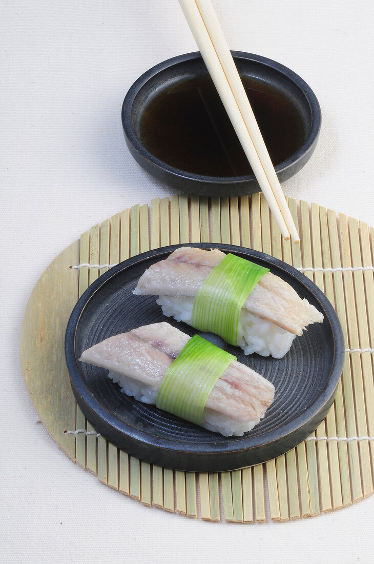 Sushi-Bar, 2 Nigiri-Sushi mit Fisch und 1 Lauchblatt umwickelt