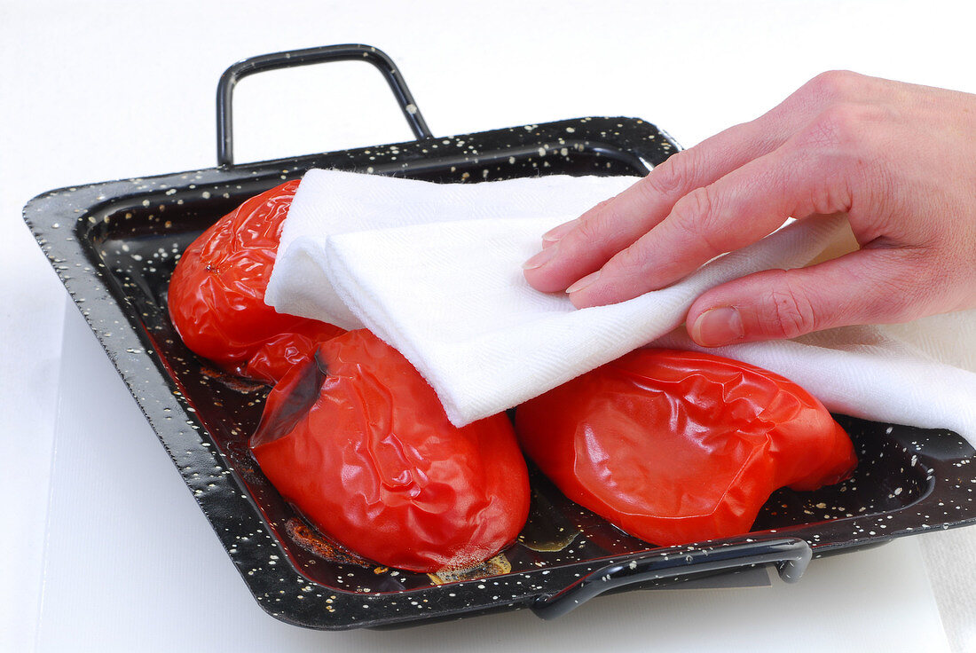 Baked peppers being dabbed with cloth in tray while preparing crostini, step 2