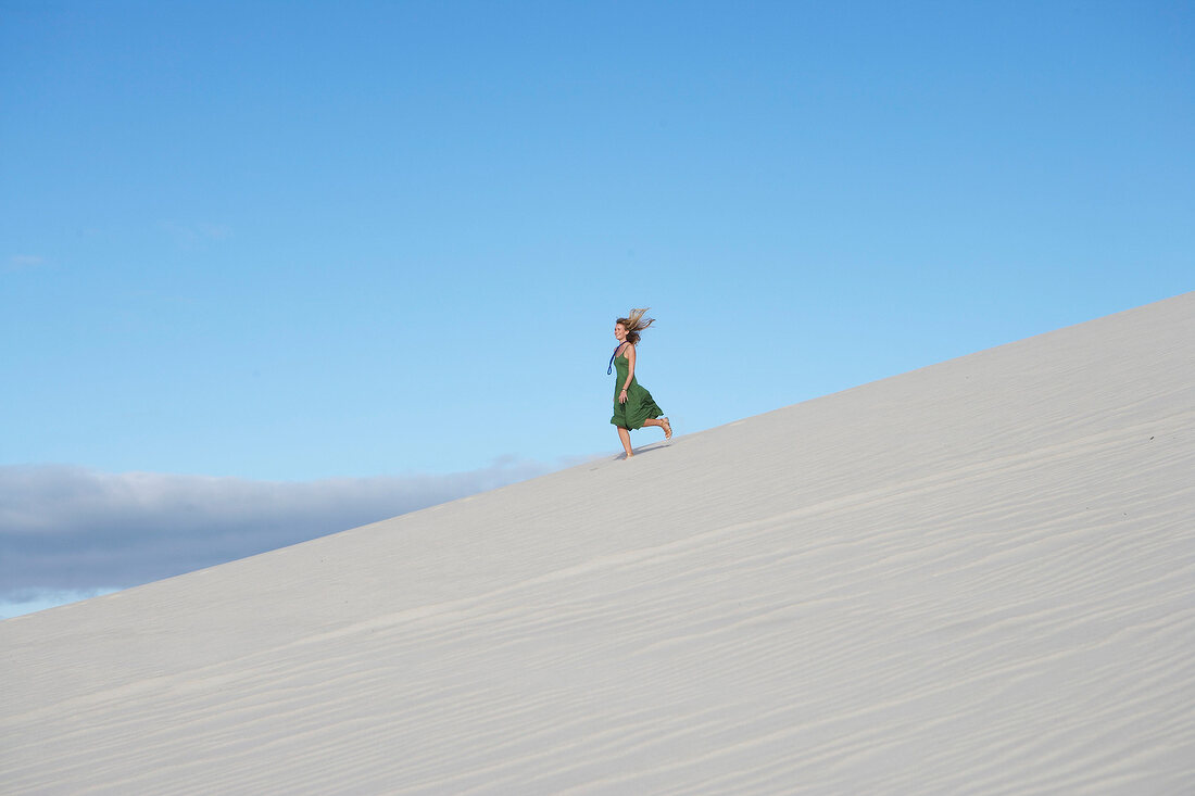 blonde Frau in grünem Kleid tanzt in der Wüste
