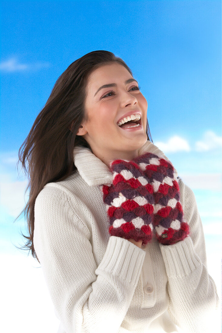 Pretty woman wearing white sweater with woollen gloves smiling while looking up