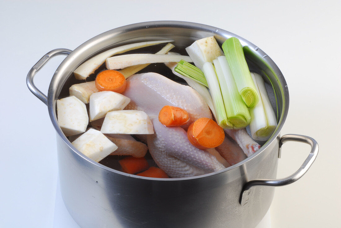 Raw chicken and vegetables in pot of water while preparing chicken broth, step 3