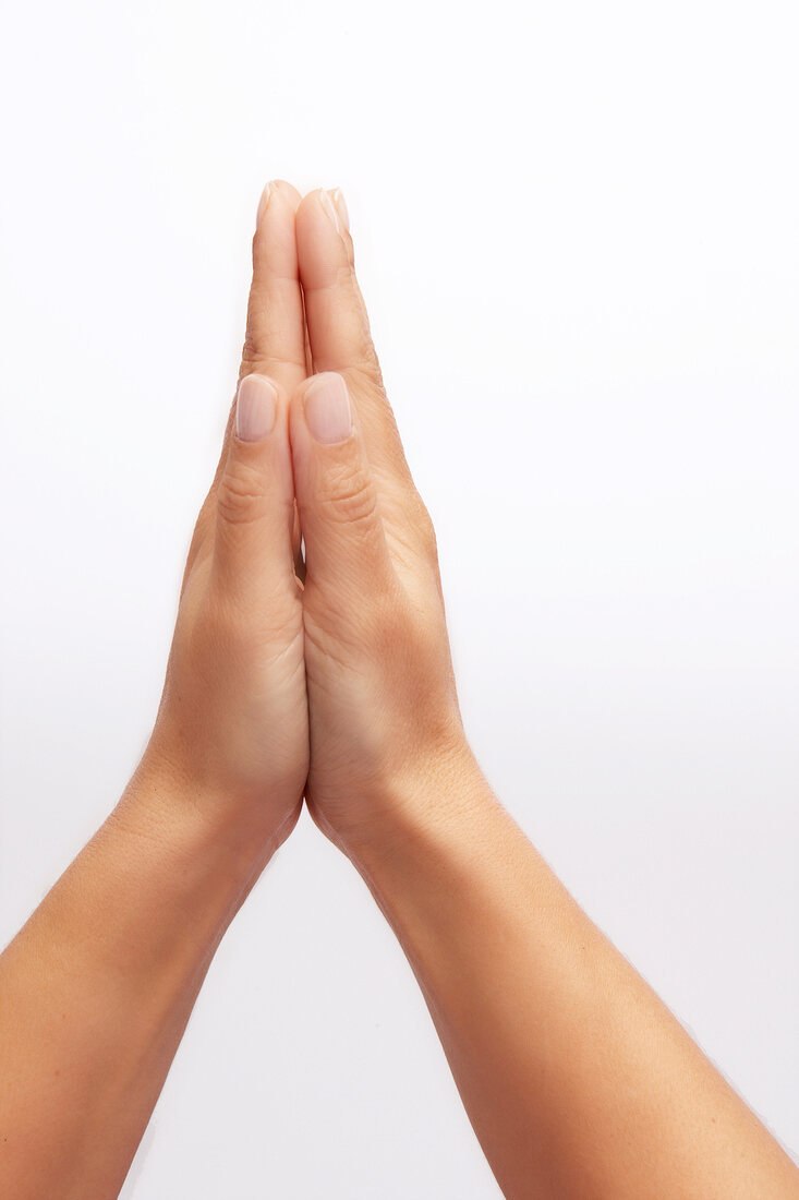 Close-up of hands clasped against white background