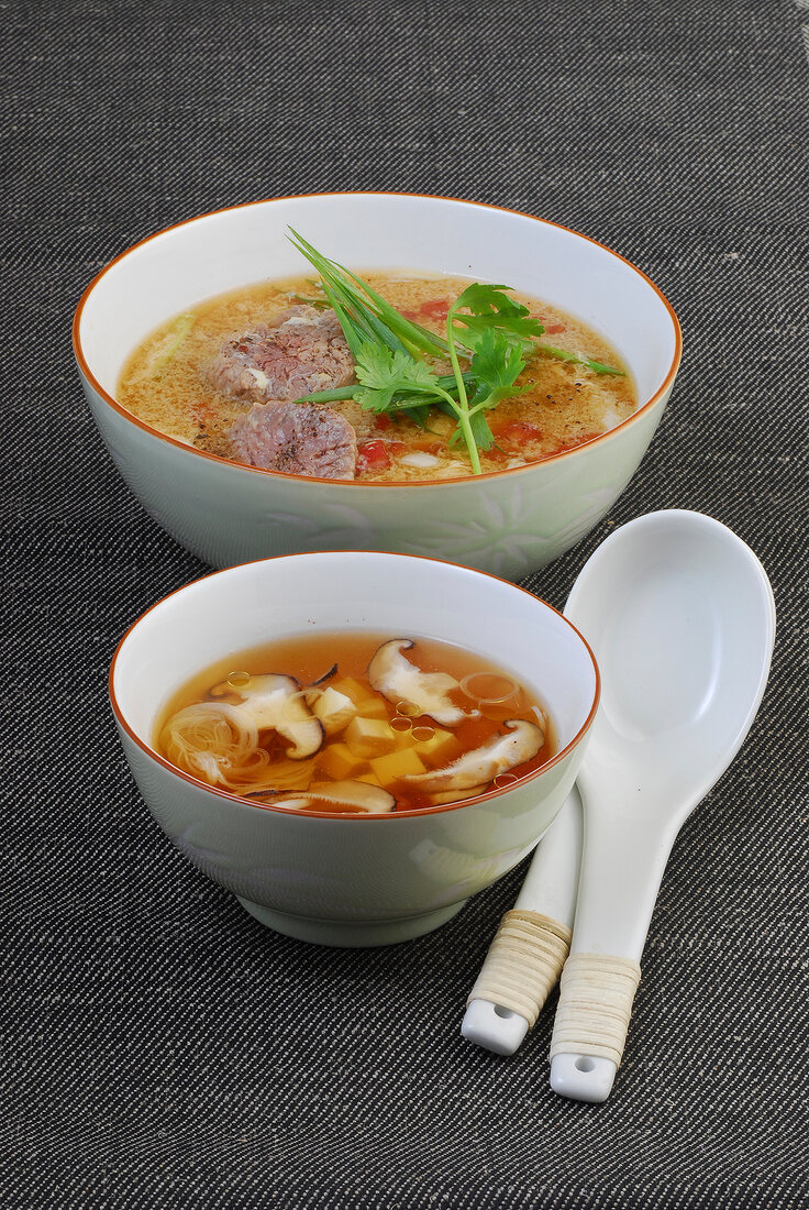 Tofu broth with mushrooms and egg drop soup with beef in bowls
