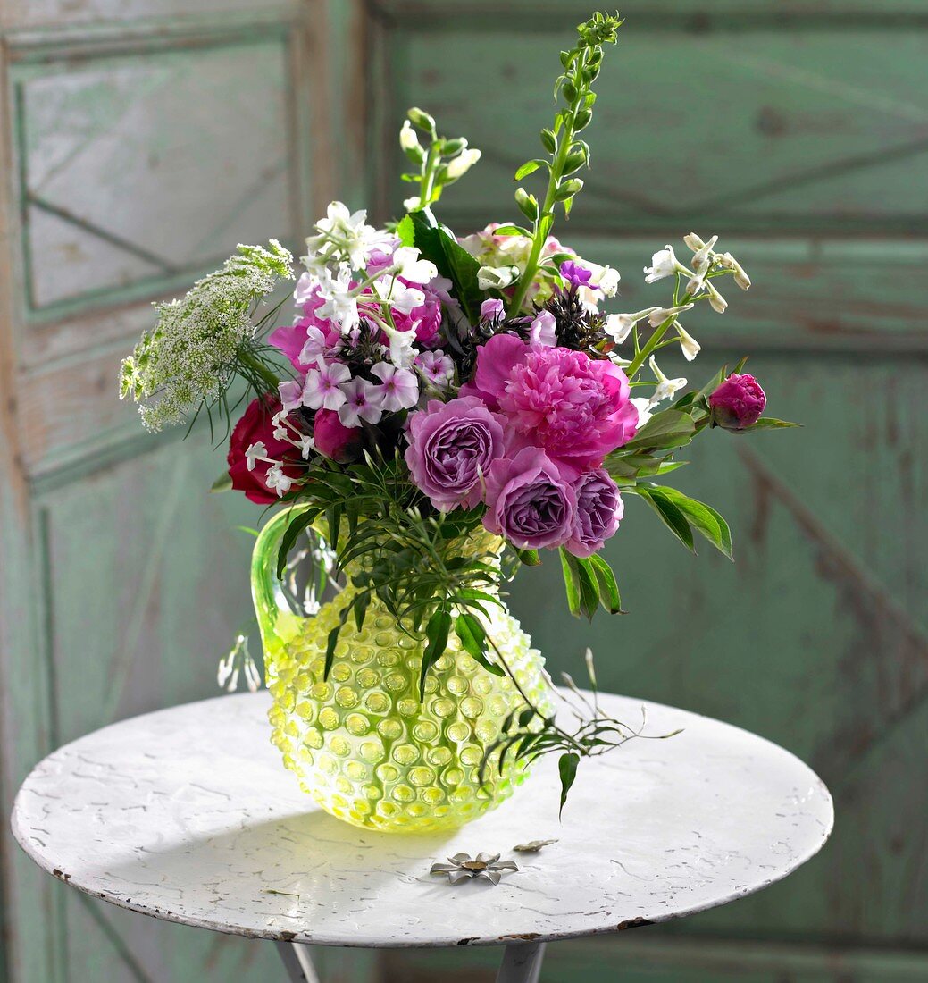 Strauß mit Sommerblumen auf einem weißen Eisentischchen