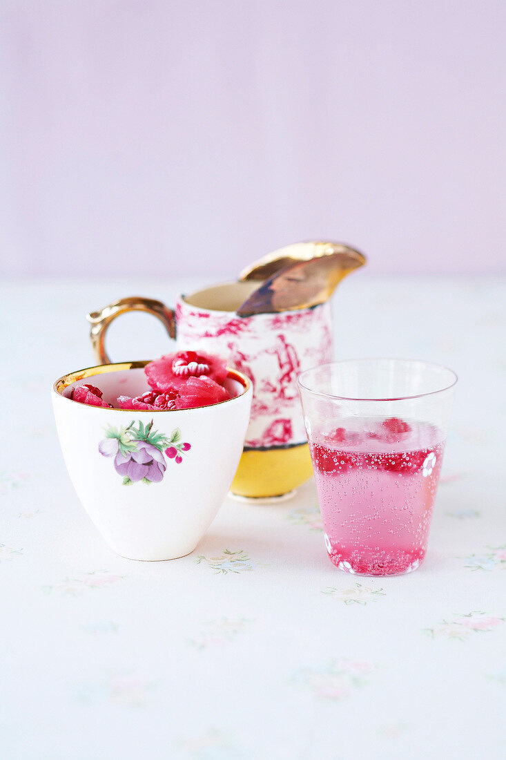 Cubes of raspberry in glass and two cups besides it