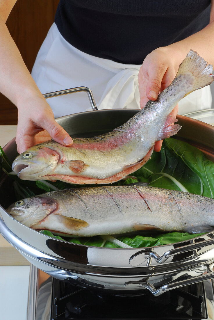 Trout being put in steamer while preparing steamed salmon trout, step 1