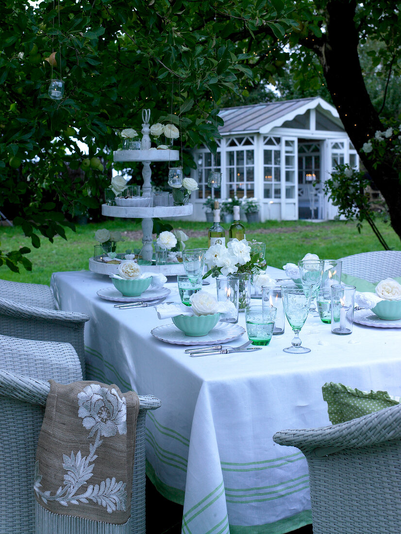 Festively decorated table with roses in green and white in garden