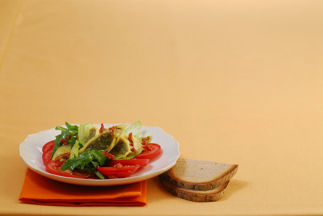 Ravioli with tomato and rocket salad on plate