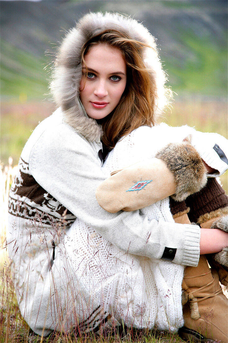 Portrait of beautiful gray eyed woman wearing knitted fur lined hood and boots, smiling