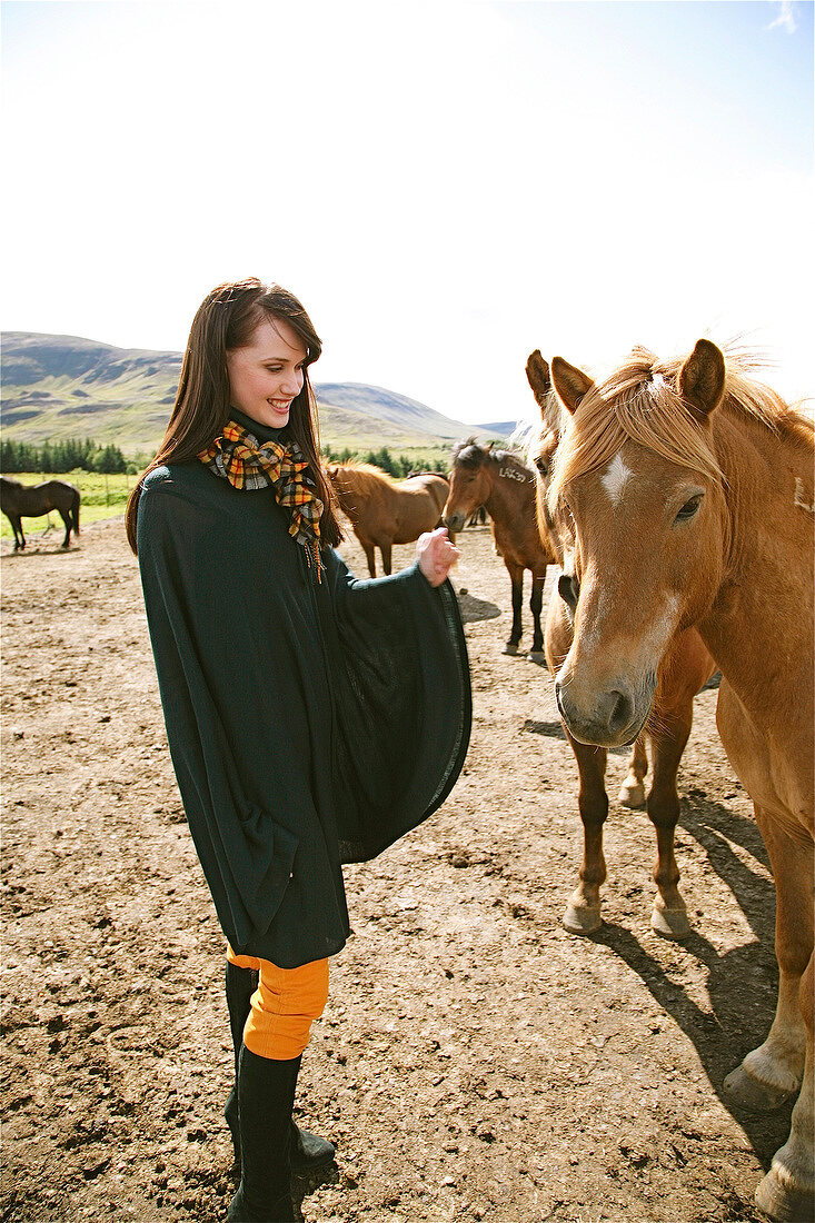 Frau in Mantel steht vor Island pferd, Hand gehoben