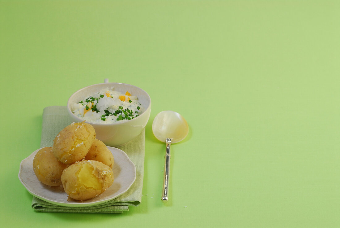 Jacket potatoes with herb quark on green background