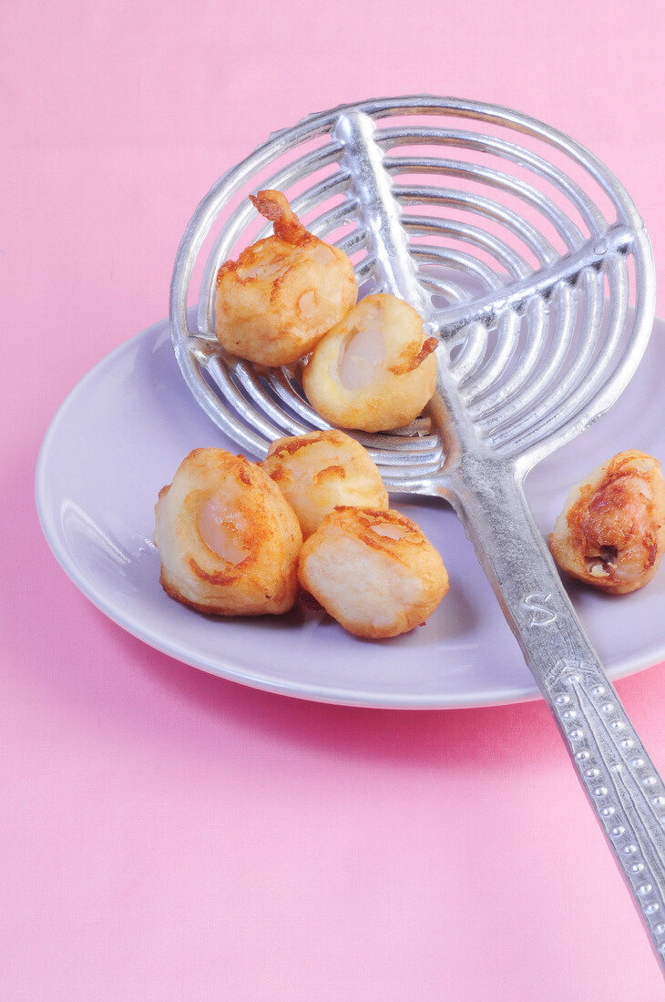 Close-up of lychees fried in coconut batter on skimmer