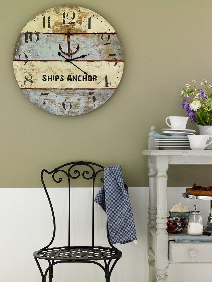 A large homemade clock made from weathered wooden boards hung on a grey kitchen wall