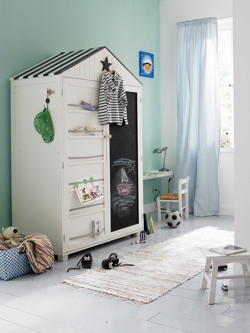 White, house-shaped wardrobe with chalkboard front
