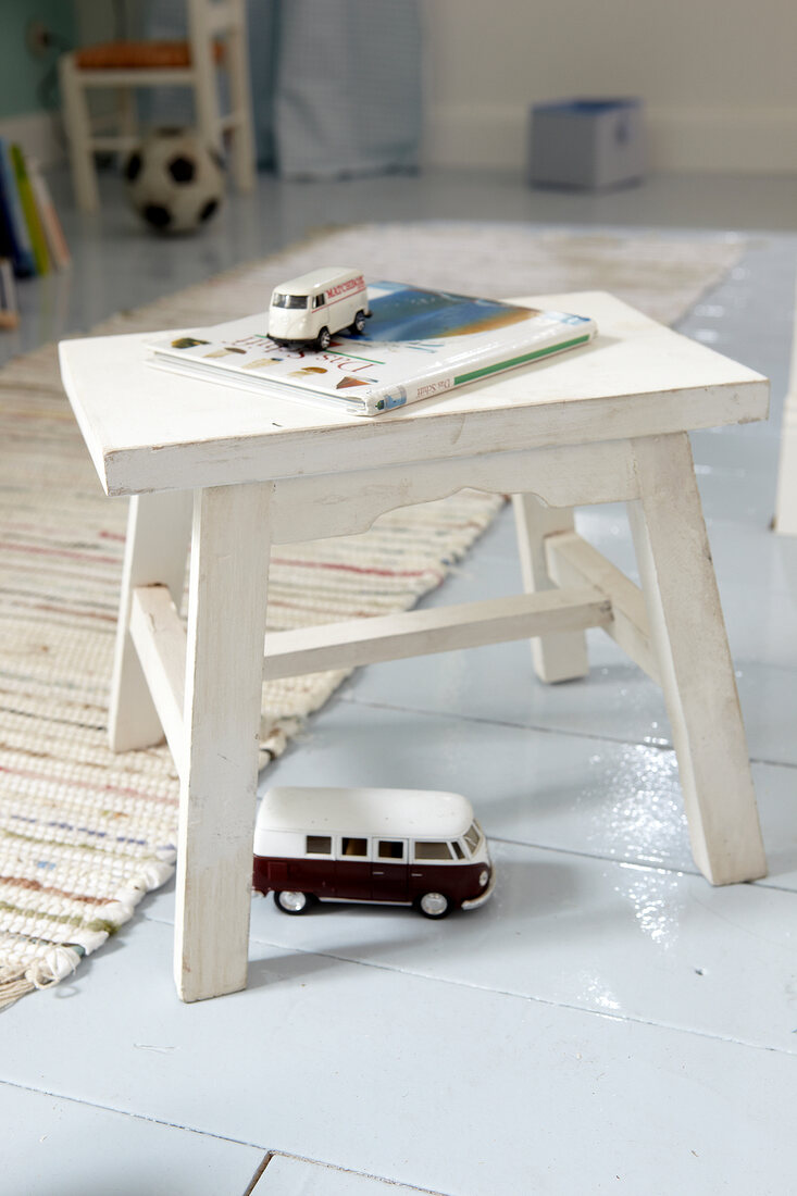White wooden stool with toy cars