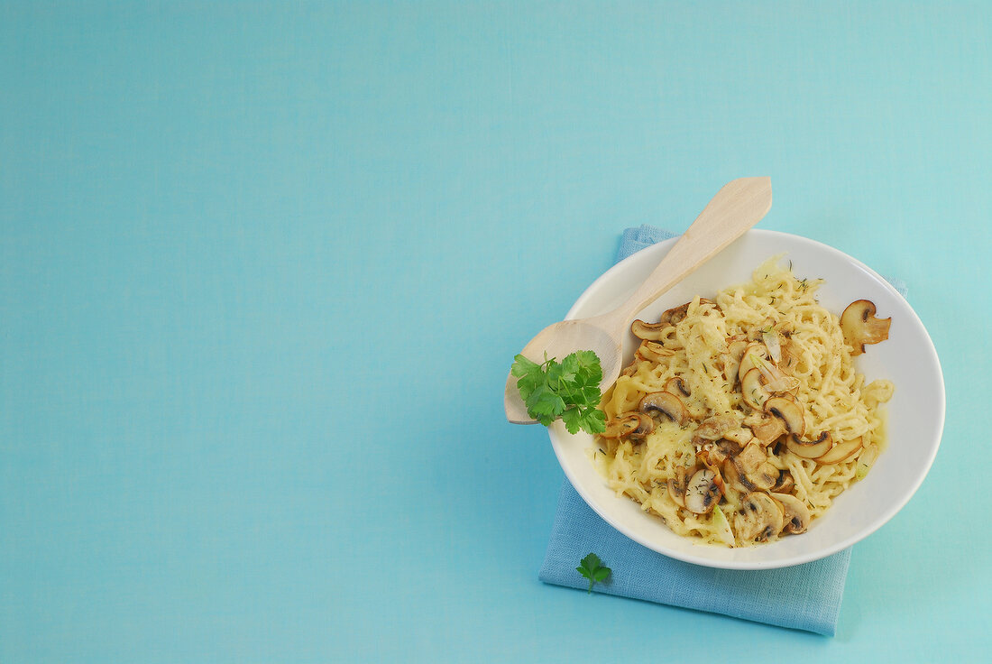 Bowl of mushroom and cheese spaetzle on blue background